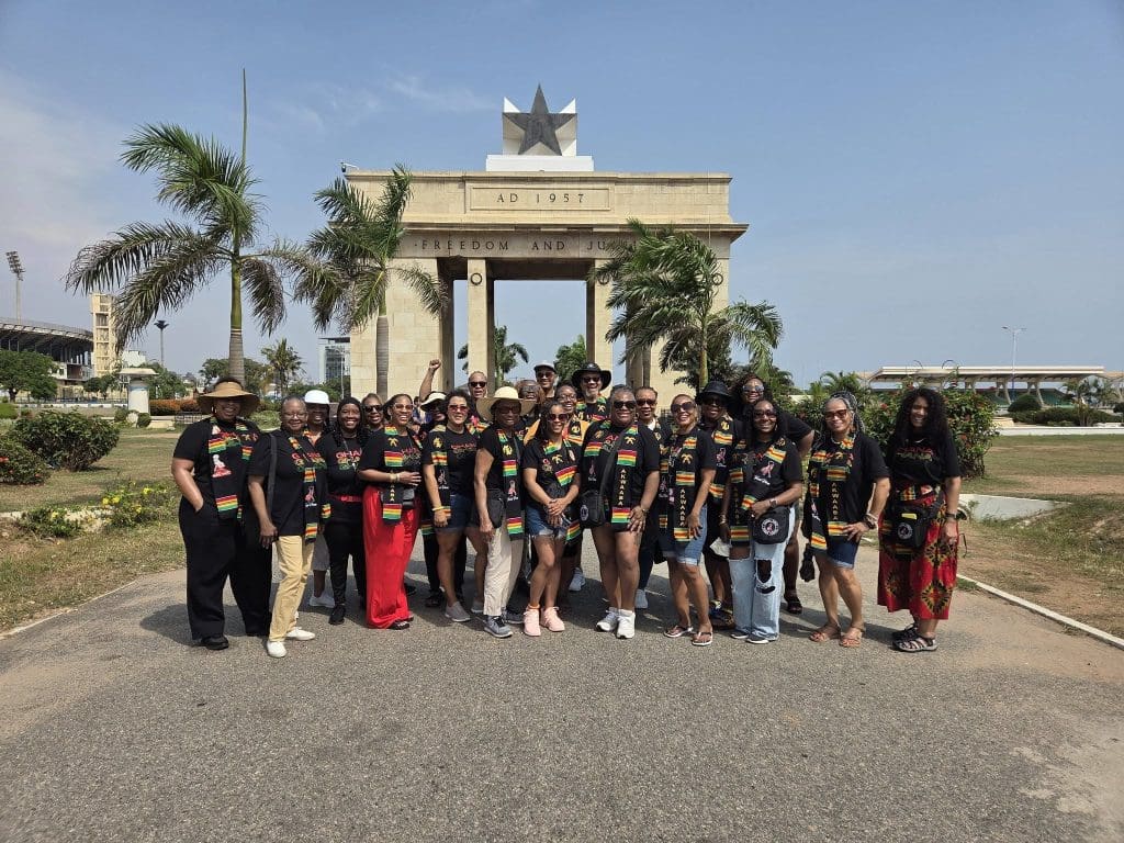 group of travel divas in front of arch in Ghana