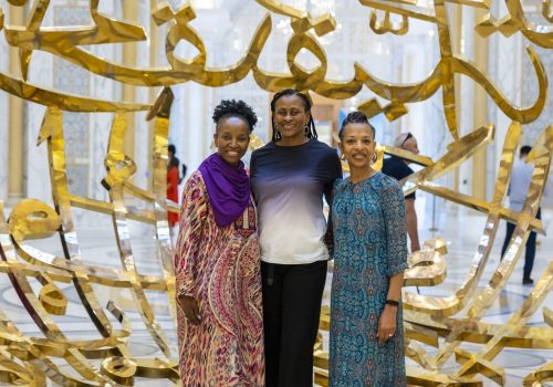 Black women in Dubai standing in front of gold sculpture