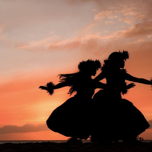 Two Hawaiian hula dancers move gracefully before the warm glow of the tropical sunset.