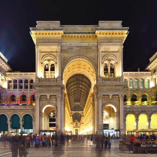 Galleria Vittorio Emanuele II entrance illuminated at night, Milan, Italy.