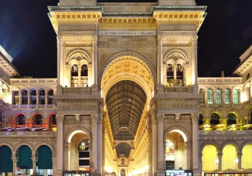 Galleria Vittorio Emanuele II entrance illuminated at night, Milan, Italy.