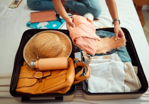 Hands, woman and suitcase on a bed for travel, adventure and summer vacation, packing and clothing. Hand, girl and luggage in a bedroom for travelling, abroad and break, relax and getaway preparation.